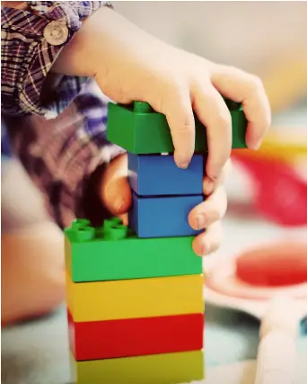 A boys small hand stacks colorful blocks