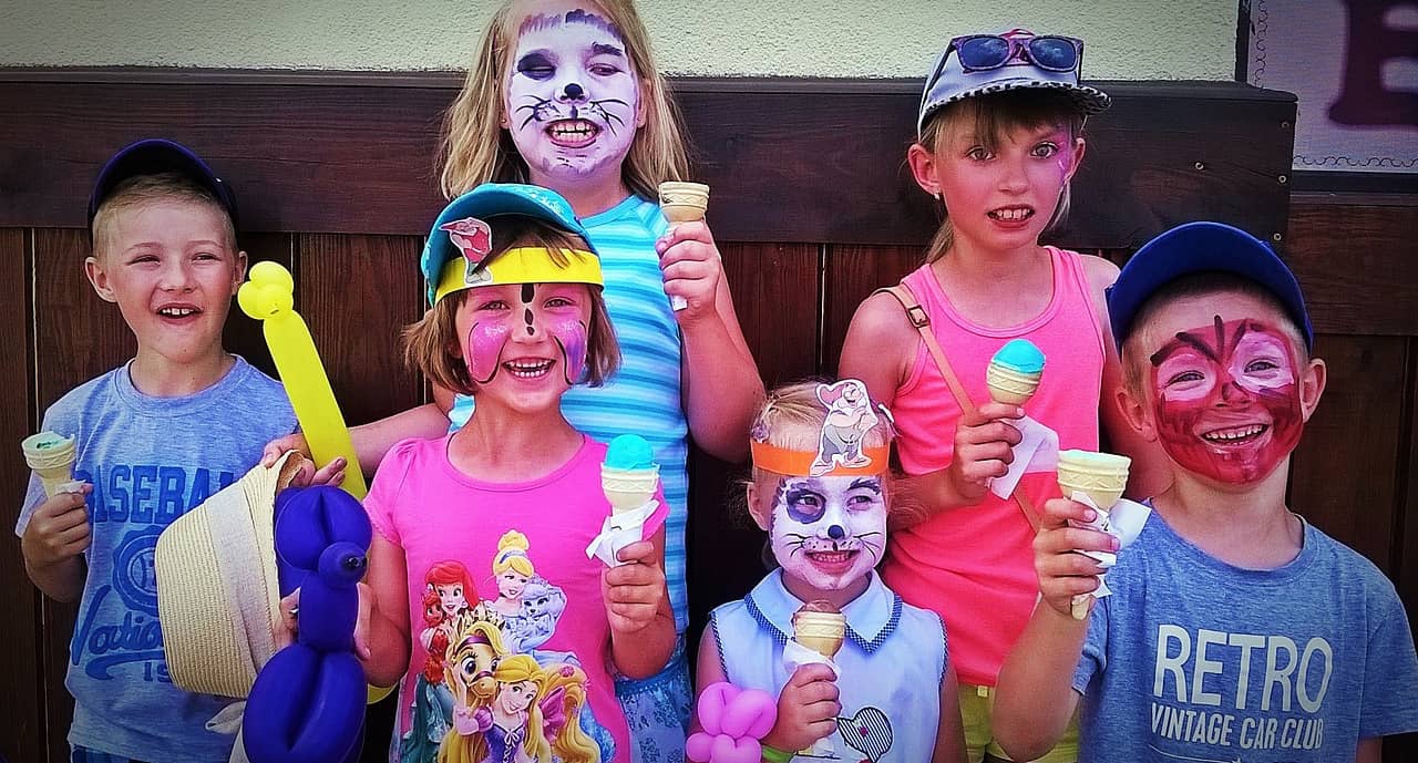 Six children of various heights display their painted faces with glee.