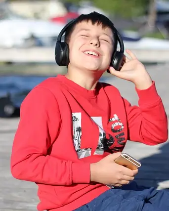 A young boy delights in listening to music through headphones.