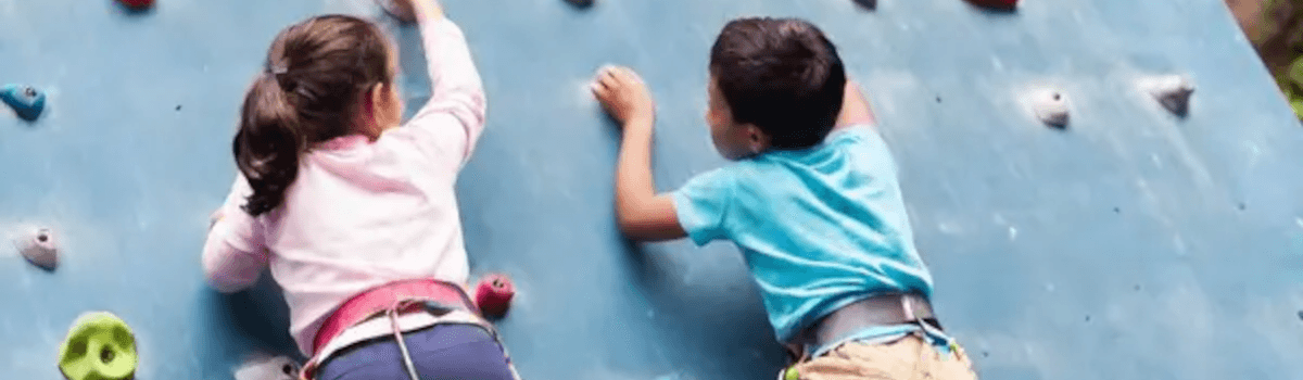 A girl and a boy climb a rock wall ltogether