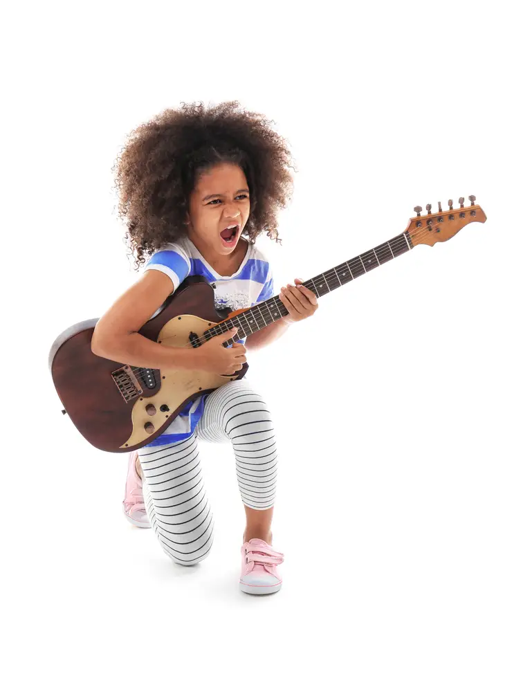 Young African American girl of about 0 years old is jamming while playing on a guitar
