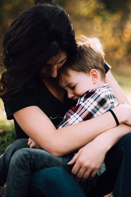 A mother holds her young son in a comforting embrace.