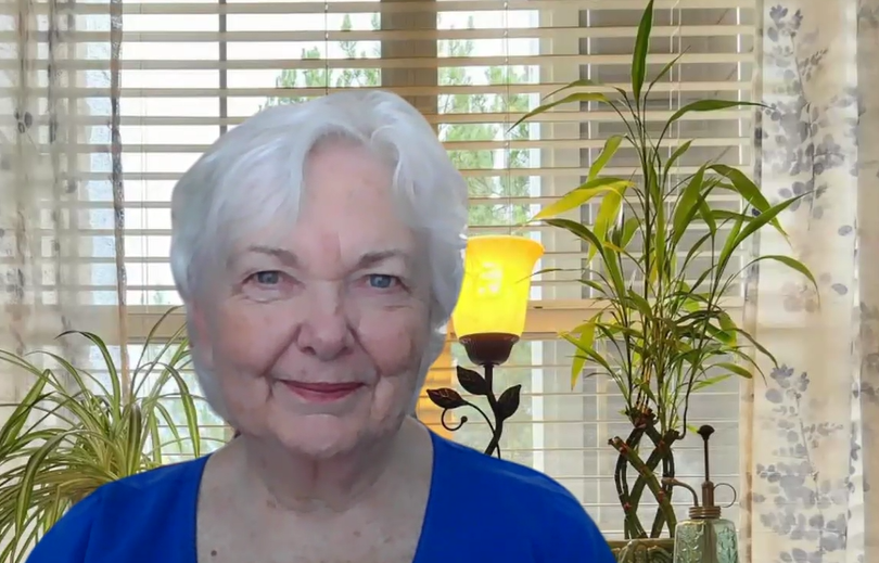Photo of Shannon Parish, Creative Life Coach, sitting in front of a sunny window with white wooden blinds, and plants in the background.